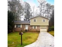 Brick and vinyl-sided house with attached garage and driveway at 3550 Leisure Ln, Atlanta, GA 30349