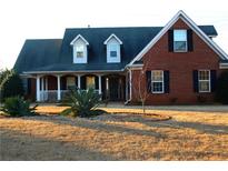 Brick home with dormer windows, porch, and landscaped yard at 321 Whitney Ln, Mcdonough, GA 30253