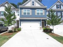 Two-story townhome with blue siding, white garage door, and landscaping at 5717 Silver Lake Dr, Mableton, GA 30126