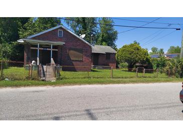 Brick home with boarded windows and chain link fence at 2026 Little Ave, North Charleston, SC 29405