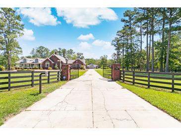 Long driveway leading to a brick home with black fence at 1426 Sc-45, McClellanville, SC 29458