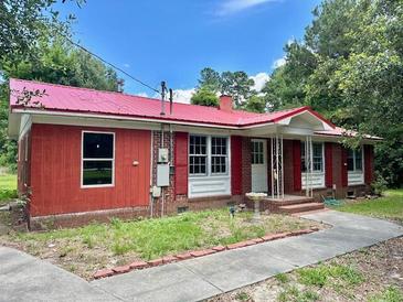 Brick ranch house with red metal roof, shutters, and a paved walkway at 2042 Sniders Highway, Walterboro, SC 29488