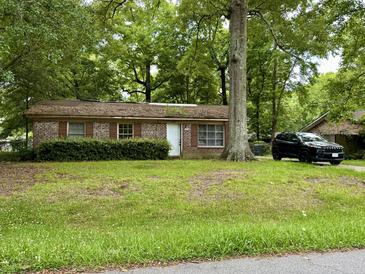 Brick ranch home with mature trees and a black SUV in the driveway at 2615 Myrtis Ln, North Charleston, SC 29406