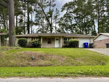 Brick ranch house with a double door entry, a single car garage, and a grassy yard at 7629 Crossgate Blvd, North Charleston, SC 29420