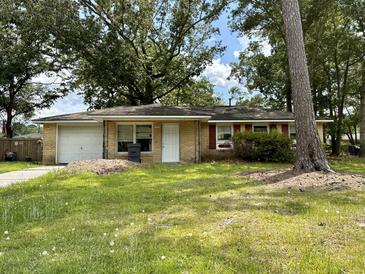 Brick ranch home with attached garage and well-maintained lawn at 7711 Desmond Ave, North Charleston, SC 29418