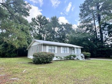 Ranch style home with gray siding, metal roof and landscaped yard at 313 Pine Needle Rd, Walterboro, SC 29488