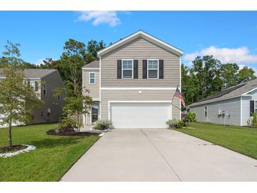 Two-story house with beige siding, a white garage door, and landscaping at 141 Lagoona Dr, Summerville, SC 29483
