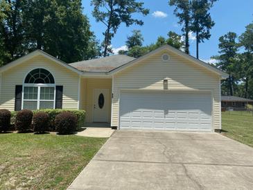 Charming yellow house with a white garage door and well-manicured lawn at 422 Constance St, Walterboro, SC 29488