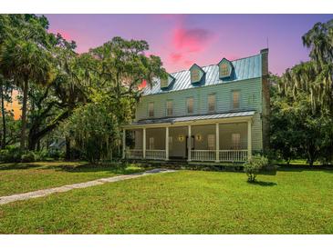 Historic home with wrap-around porch and lush landscaping at 8083 Point Of Pines Rd, Edisto Island, SC 29438