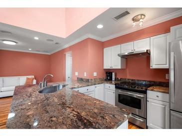 Modern kitchen with granite countertops, stainless steel appliances, and coral-colored walls at 1616 Live Oak Park, Seabrook Island, SC 29455