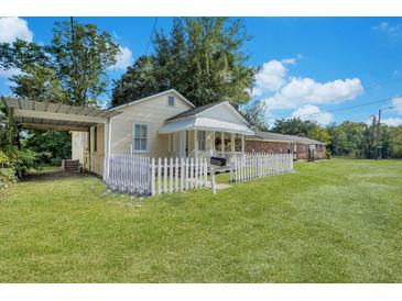 Charming yellow cottage with white picket fence and landscaped lawn at 1927 Iris St, North Charleston, SC 29405