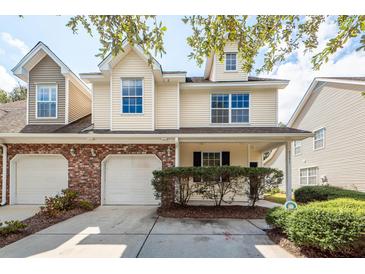 Tan two-story townhome with two-car garage and manicured landscaping at 1151 Saint Pauls Parrish Ln, Johns Island, SC 29455