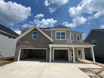 Two-story house with a brick and beige exterior, three-car garage and a long driveway at 107 Grange Cir, Summerville, SC 29486