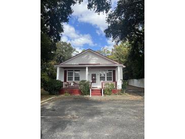 Charming white cottage with red trim, front porch, and ample parking at 507 E 5Th N St, Summerville, SC 29483