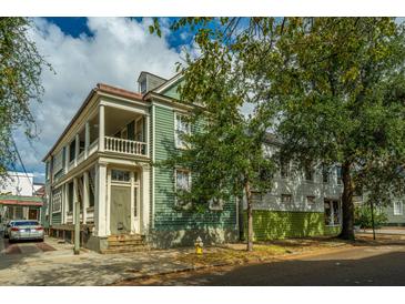 Charming two-story green house with a white porch at 64 Radcliffe St, Charleston, SC 29403