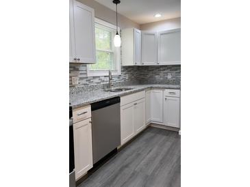 Modern kitchen with white cabinets, granite counters, and stainless steel appliances at 318 Bedford Rd, Cross, SC 29436