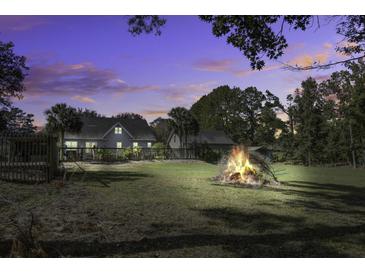 Large backyard with a bonfire at sunset at 443 Lazy Hill Rd, Moncks Corner, SC 29461