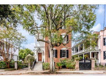 Brick home with three stories, front porch, and large tree at 52 Hasell St, Charleston, SC 29401