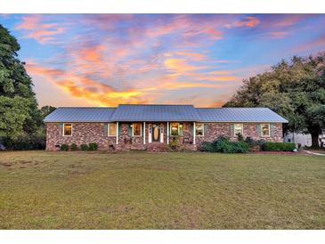 Brick ranch house with metal roof and landscaped yard at 203 Hickory Nut Drive, Harleyville, SC 29448