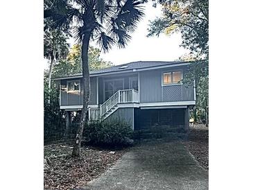 Raised cottage style home with stairs and palm tree at 21 Twin Oaks (1/8 Share) Ln, Isle of Palms, SC 29451