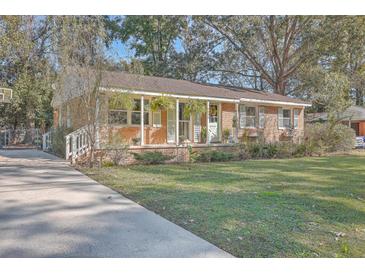 Brick ranch home with covered porch, mature trees, and a spacious yard at 1839 Manigault Pl, Charleston, SC 29407