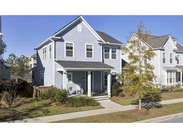 Two-story light blue house with a front porch and rocking chairs, well-manicured lawn at 513 Scholar Way, Summerville, SC 29486