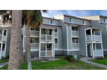 Gray multi-unit building with white railings and stairs, surrounded by palm trees and grass at 30 Mariners Cay Dr, Folly Beach, SC 29439