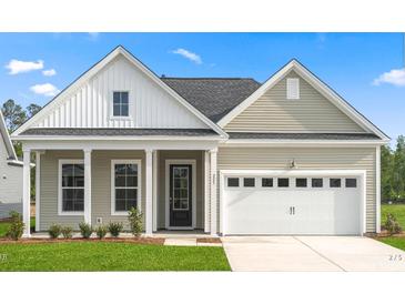 Tan two-story house with white accents, a covered porch, and a two-car garage at 716 Breakers Reef Ln, Huger,  29450