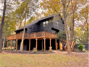 Two-story home with large deck, surrounded by trees, showcasing stylish exterior at 6464 St Anthony Dr, Hollywood, SC 29449