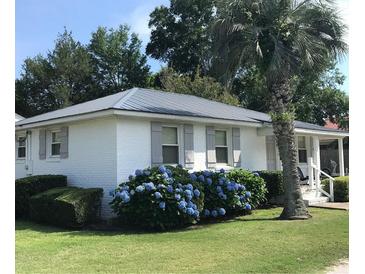 Charming white brick ranch home with gray shutters, lush landscaping, and a metal roof at 509 Live Oak Dr, Mount Pleasant, SC 29464