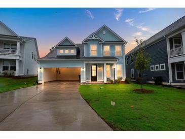 Two-story light blue house with attached garage and well-manicured lawn at dusk at 709 Maynard Ln, Summerville, SC 29486