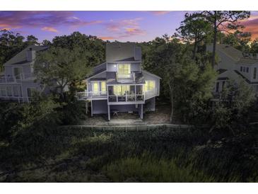 Elevated view of charming two-story home with deck, water views, and sunset at 32 Marsh Island (4 Shares) Ln, Isle of Palms, SC 29451