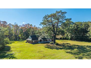 Brick house with large yard and tree, offering a serene setting at 4751 River Rd, Johns Island, SC 29455