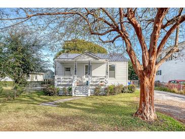 Charming white cottage with a metal roof, front porch, and landscaped yard at 1328 Cottonwood St, Charleston, SC 29403