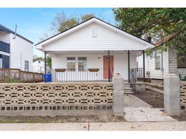 Charming white cottage with a coral door, concrete walkway, and a decorative block wall at 31 Allway St, Charleston, SC 29403