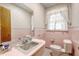 Pink tiled bathroom with vanity, toilet, and window at 1447 Fort Lamar Rd, Charleston, SC 29412