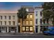 Charming three-story home with a yellow facade and a palm tree in front at 29 Broad St # C, Charleston, SC 29401