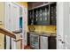 Stylish wet bar with dark cabinetry, beverage fridge, and glass shelving at 29 Broad St # C, Charleston, SC 29401