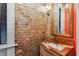 Elegant powder room boasts exposed brick, marble vanity, and gold accents at 29 Broad St # C, Charleston, SC 29401