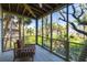 Screened porch with wooden furniture and lush landscaping views at 403 Pelican Flight Dr, Dewees Island, SC 29451