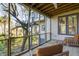 Relaxing screened porch with wooden furniture and tranquil wooded views at 403 Pelican Flight Dr, Dewees Island, SC 29451