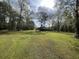 Spacious grassy yard with mature trees and a glimpse of a structure in the background at 138 Waddell Ln, Ridgeville, SC 29472