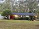 Detached garage with a red door and carport, surrounded by trees at 138 Waddell Ln, Ridgeville, SC 29472
