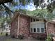 Brick home with large windows and mature trees at 1056 Yorktown Dr, Charleston, SC 29412