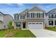 Two-story beige house with a large white garage door and a landscaped lawn at 115 Ashley Cove Way, Summerville, SC 29483