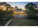Evening view of a luxurious waterfront home with a lighted deck and private dock at 3067 Marshgate Dr, Seabrook Island, SC 29455