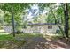 Tan mobile home nestled in a wooded lot with grassy yard at 121 Paisan Rd, Summerville, SC 29483