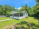 Side view of a white one-story house with a screened porch and green lawn at 212 Hickory St, Walterboro, SC 29488