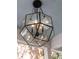 Close-up of an ornate geometric chandelier with glass panels and Edison bulbs set against a light blue ceiling at 3 38Th Ave, Isle of Palms, SC 29451