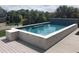 A luxurious, rectangular pool with stone and light blue tile, plus a built-in seat on a wood deck at 3 38Th Ave, Isle of Palms, SC 29451